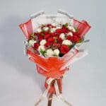 A breathtaking red and white roses bouquet, elegantly wrapped in matching red and white paper, accented with lush greenery for a touch of freshness.