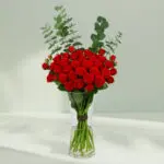 A bunch of Fresh red roses and eucalyptus arranged in a cute glass vase