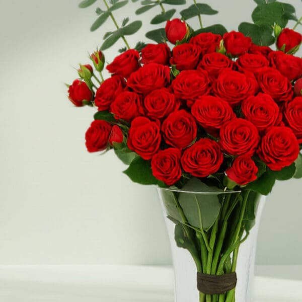 A bunch of Fresh red roses and eucalyptus arranged in a cute glass vase